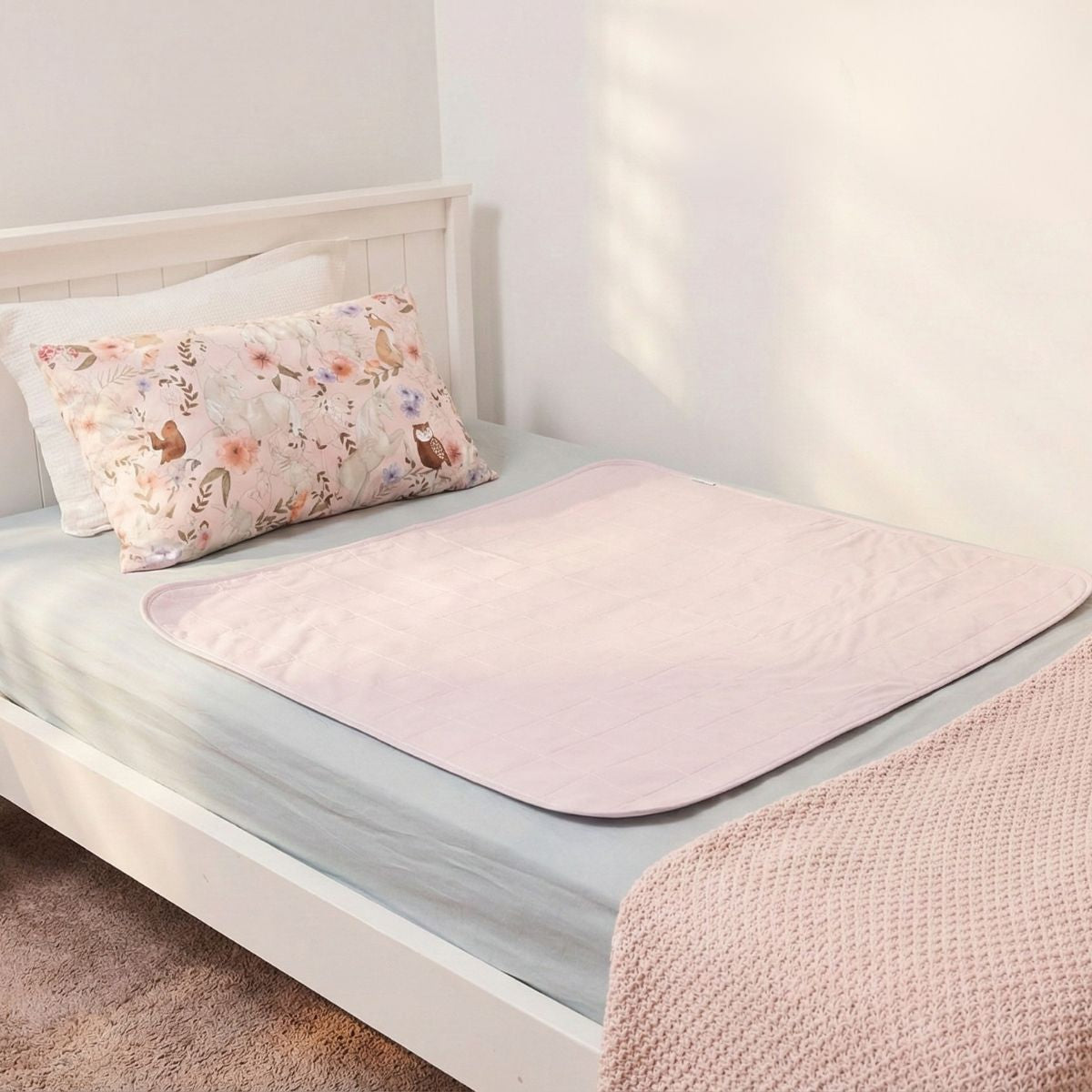 מגן מזרן סופג מבית ברולי על מיטת יחיד, צבע ורוד