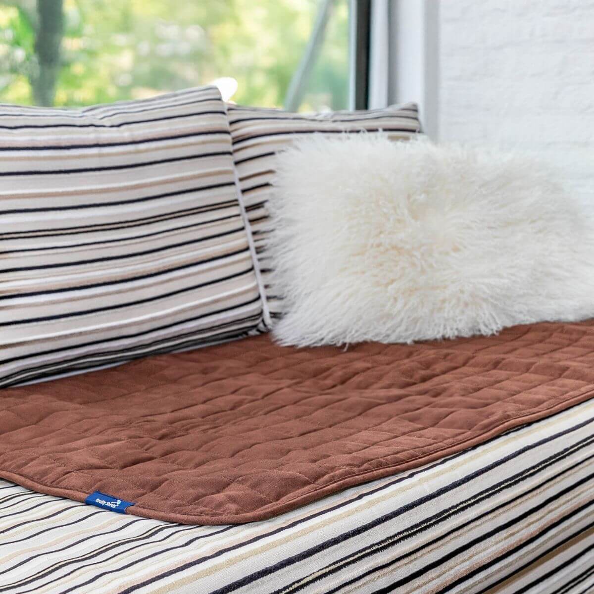 מגן מושב גדול צבע חום כהה פרוס על ספה