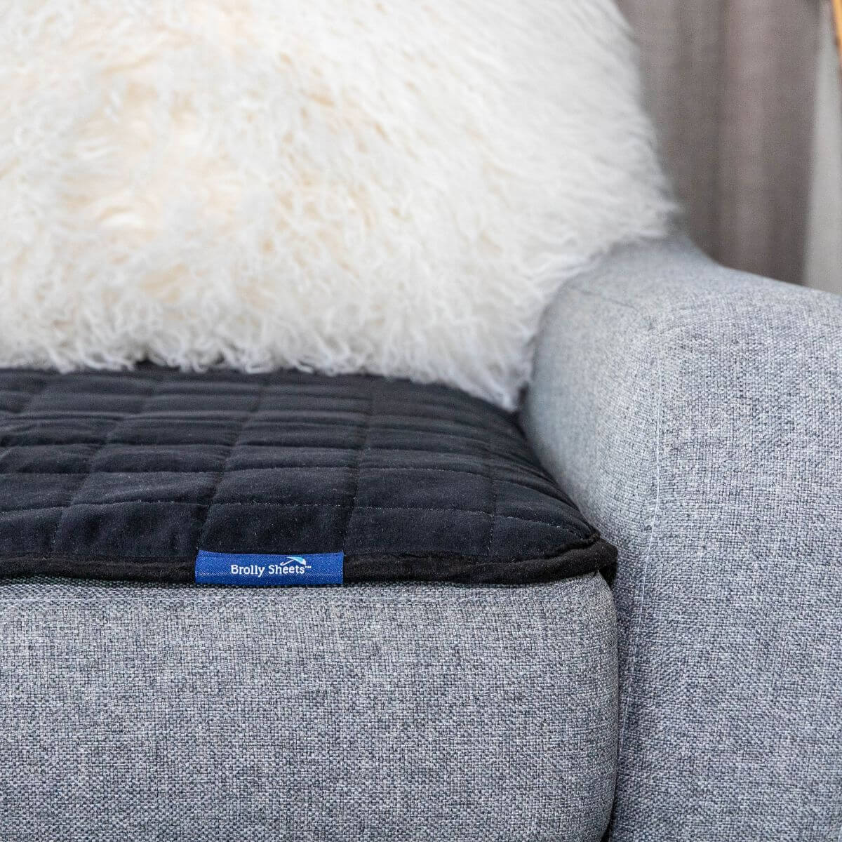 מגן מושב מבית ברולי בצבע שחור, מונח על כורסא