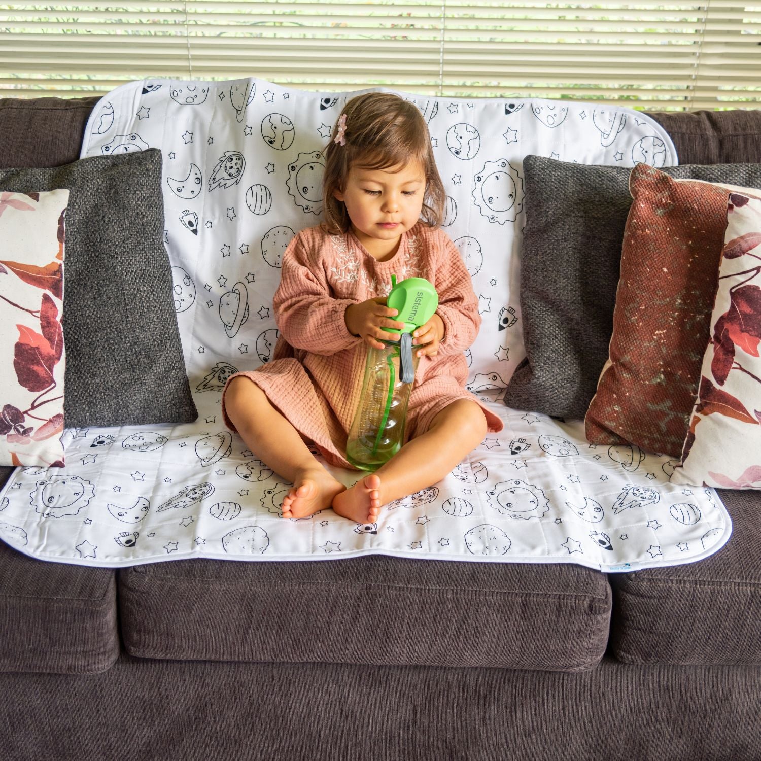 פעוטה יושבת על מגן מזרן סופג דגם גלקסיה